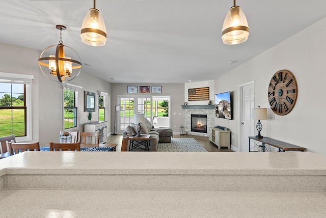 living room with a notable chandelier, a fireplace, hardwood / wood-style floors, and a wealth of natural light