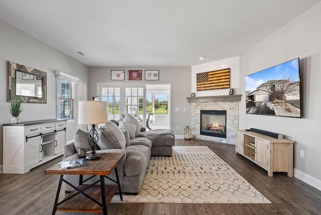 living room with dark hardwood / wood-style floors and a stone fireplace