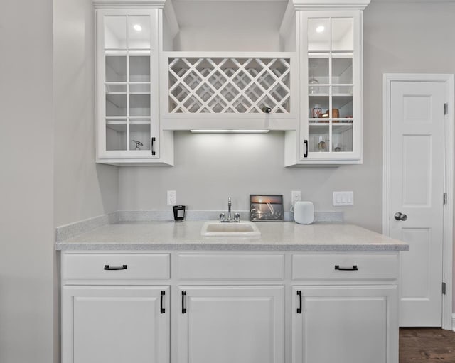 bar with dark hardwood / wood-style floors, sink, and white cabinets