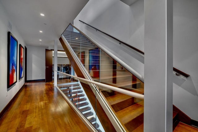 staircase with independent washer and dryer and hardwood / wood-style floors