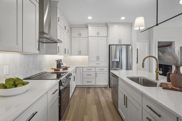 kitchen featuring white cabinetry, hanging light fixtures, wall chimney exhaust hood, and appliances with stainless steel finishes