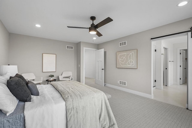 carpeted bedroom with ceiling fan and a barn door