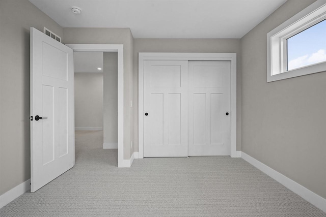 unfurnished bedroom featuring light colored carpet and a closet