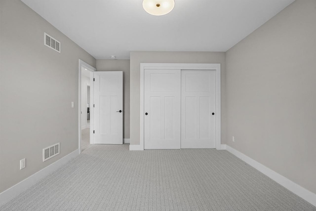 unfurnished bedroom with light colored carpet and a closet