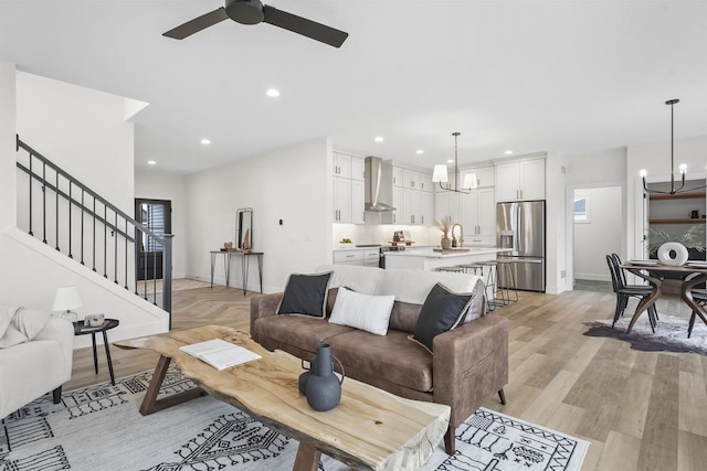 living room featuring sink, ceiling fan with notable chandelier, and light hardwood / wood-style flooring