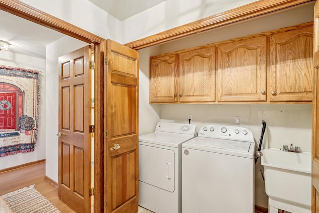 laundry room featuring cabinets, sink, washer and clothes dryer, and light wood-type flooring