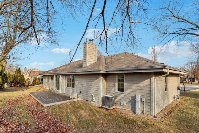 rear view of property with a patio, central air condition unit, and a lawn