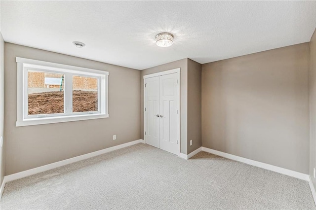 unfurnished bedroom featuring light carpet, a textured ceiling, and a closet