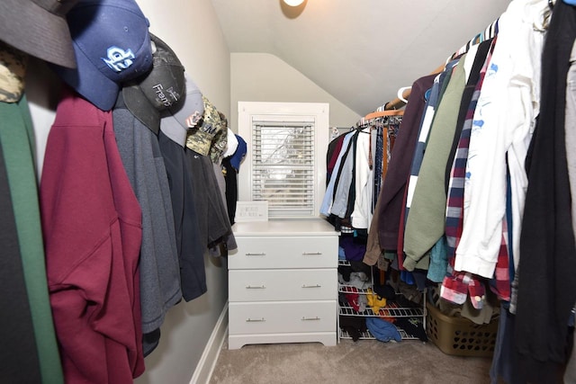 walk in closet with light carpet and lofted ceiling