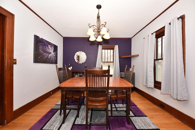 dining space featuring hardwood / wood-style flooring, a healthy amount of sunlight, crown molding, and a chandelier