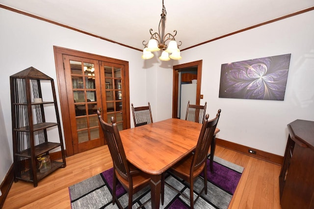 dining space with crown molding, a chandelier, light wood-type flooring, and french doors