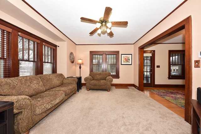 carpeted living room featuring ornamental molding and ceiling fan