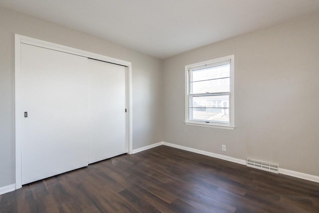 unfurnished bedroom featuring dark wood-type flooring and a closet