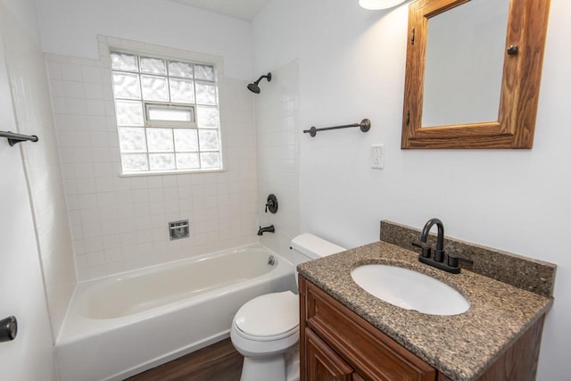 full bathroom featuring vanity, hardwood / wood-style floors, tiled shower / bath combo, and toilet