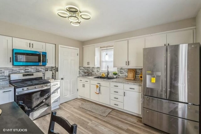 kitchen featuring sink, appliances with stainless steel finishes, backsplash, light hardwood / wood-style floors, and white cabinets