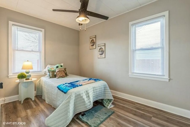 bedroom featuring ceiling fan, hardwood / wood-style floors, and multiple windows