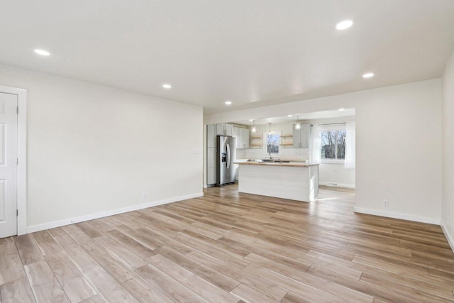 unfurnished living room featuring sink and light wood-type flooring