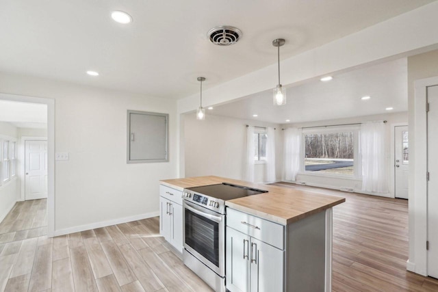 kitchen with butcher block countertops, stainless steel electric range oven, hanging light fixtures, a kitchen island, and light wood-type flooring