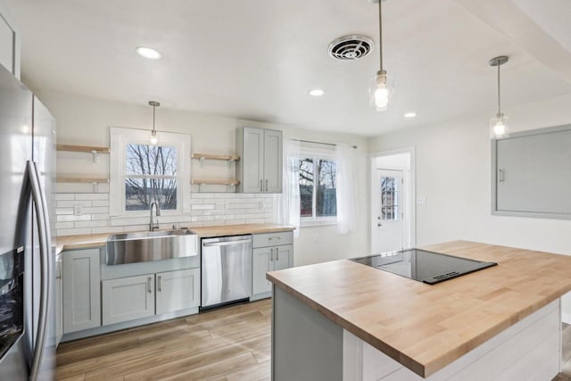 kitchen with butcher block counters, hanging light fixtures, gray cabinets, and appliances with stainless steel finishes