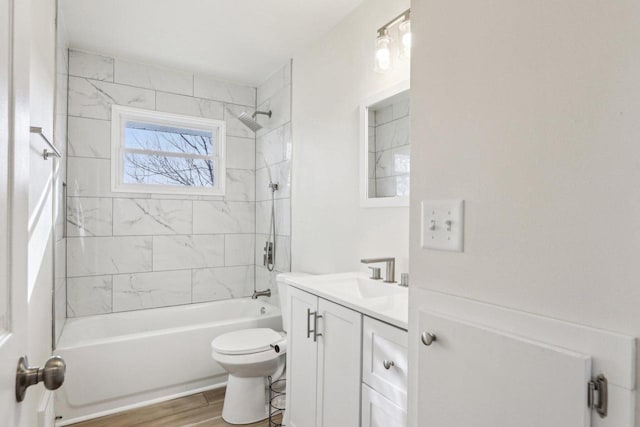 full bathroom featuring vanity, hardwood / wood-style floors, tiled shower / bath combo, and toilet