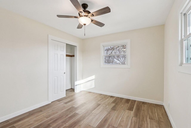 unfurnished bedroom with multiple windows, ceiling fan, light wood-type flooring, and a closet