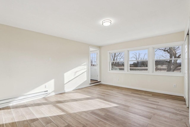 unfurnished room featuring baseboard heating and light wood-type flooring