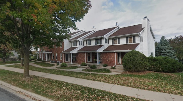 view of front of home with brick siding and a chimney