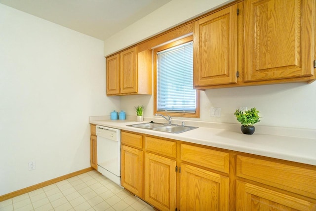 kitchen with a sink, baseboards, light countertops, and dishwasher