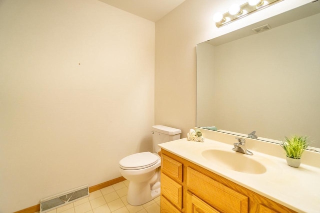 bathroom featuring toilet, vanity, baseboards, visible vents, and tile patterned floors