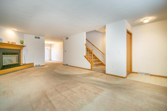 unfurnished living room featuring carpet, stairs, visible vents, and a tiled fireplace