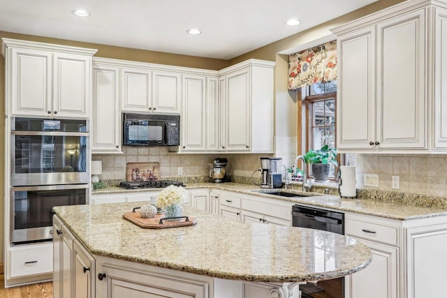 kitchen with light stone counters, sink, a kitchen island, and black appliances