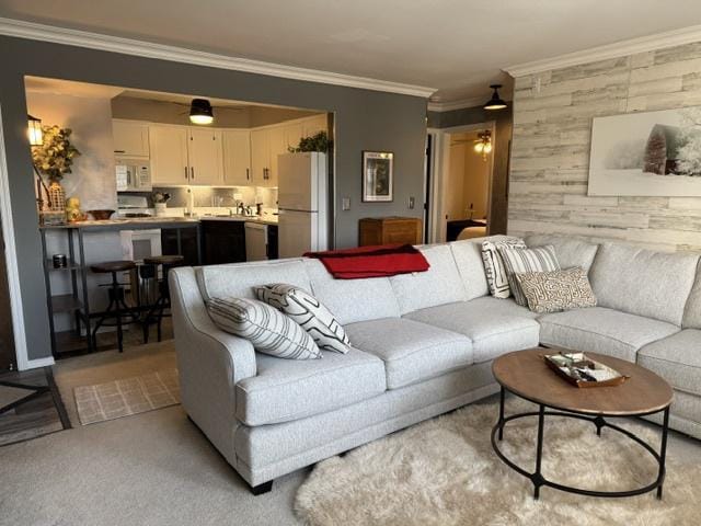 carpeted living room with ornamental molding and ceiling fan