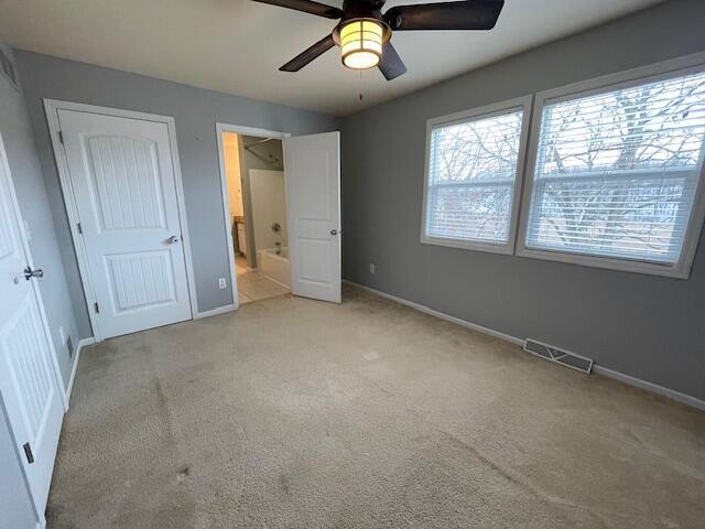 unfurnished bedroom with light carpet, connected bathroom, and ceiling fan