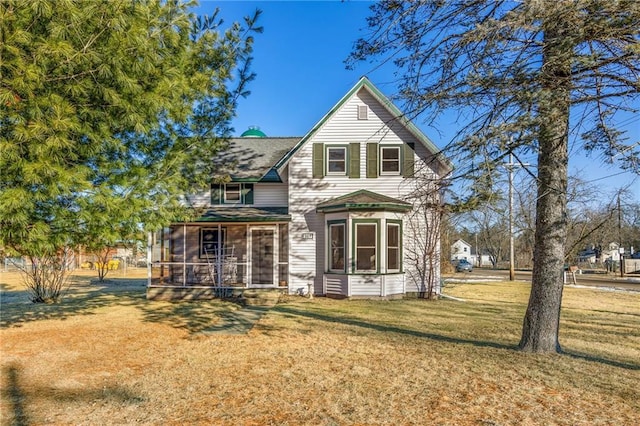 back of property featuring a sunroom and a lawn