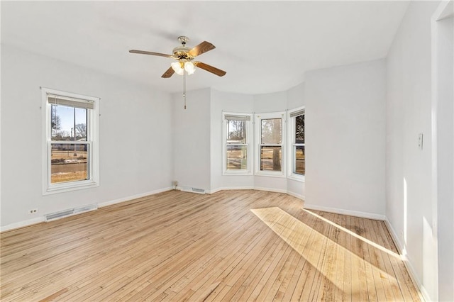 empty room featuring ceiling fan, a wealth of natural light, and light hardwood / wood-style floors