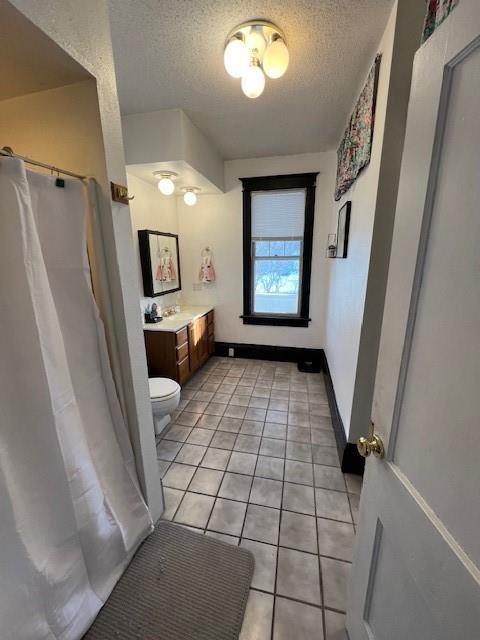 bathroom with vanity, toilet, tile patterned flooring, and a textured ceiling