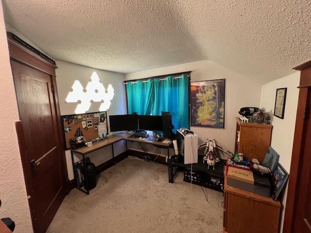 carpeted office with vaulted ceiling and a textured ceiling