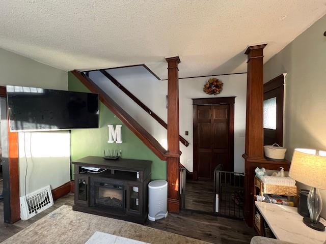 living room with decorative columns, dark hardwood / wood-style flooring, and a textured ceiling