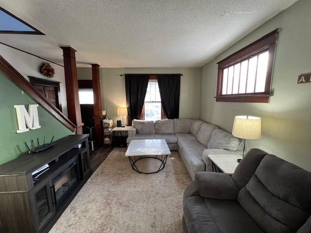 living room featuring decorative columns and a textured ceiling