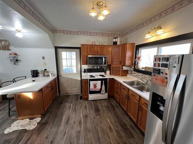 kitchen featuring sink, dark hardwood / wood-style floors, a kitchen breakfast bar, kitchen peninsula, and stainless steel appliances