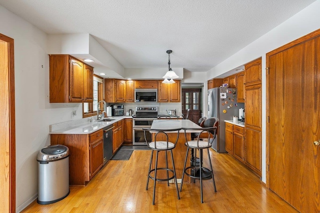 kitchen with appliances with stainless steel finishes, a breakfast bar, decorative light fixtures, sink, and a center island