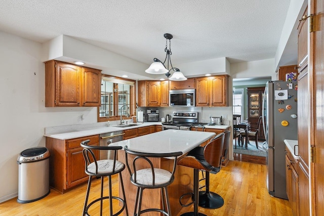 kitchen with stainless steel appliances, sink, a kitchen island, and light wood-type flooring