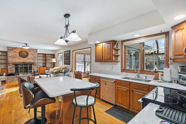 kitchen featuring pendant lighting, a fireplace, sink, a kitchen bar, and light hardwood / wood-style flooring