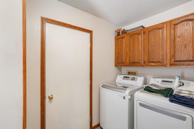 laundry room with cabinets, washer and dryer, and a textured ceiling