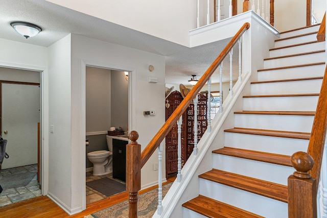 stairway with hardwood / wood-style flooring and a textured ceiling