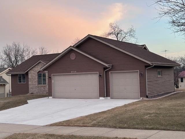 single story home featuring a garage and a yard