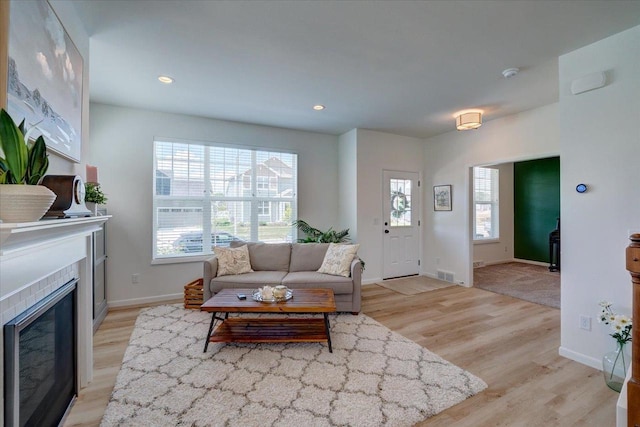 living room featuring light hardwood / wood-style flooring and a tile fireplace