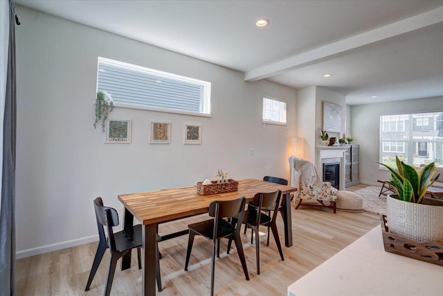 dining room with beamed ceiling and light hardwood / wood-style flooring