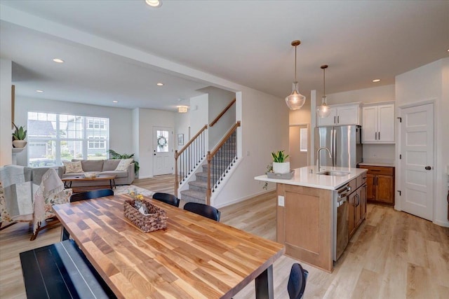 kitchen featuring sink, an island with sink, pendant lighting, stainless steel appliances, and white cabinets