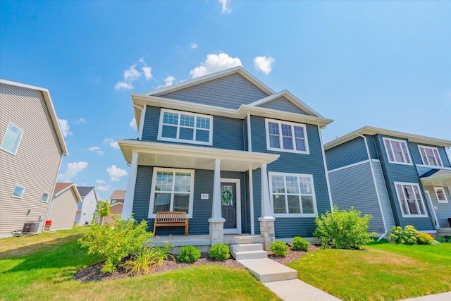 craftsman inspired home with a front lawn, covered porch, and central air condition unit